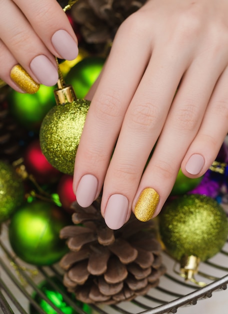 Beautiful female hand with beige nail design. Christmas manicure.