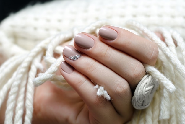 Beautiful female hand with beige nail design.