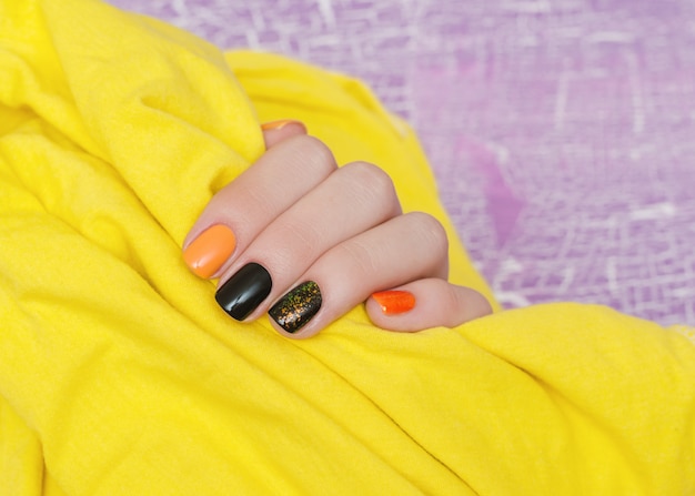 Bella mano femminile con nail art arancione e nero