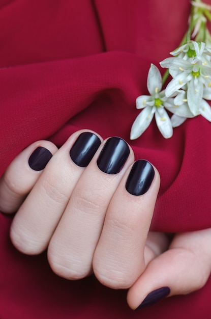 Beautiful female hand with purple nail design.