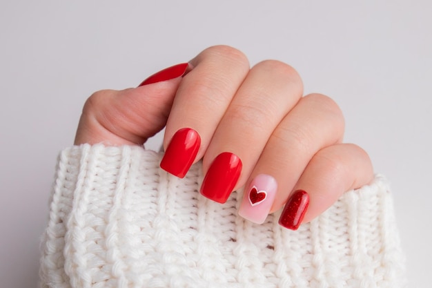Красивая женская рука с красным маникюром ногти сердце и дизайн дня святого Валентина