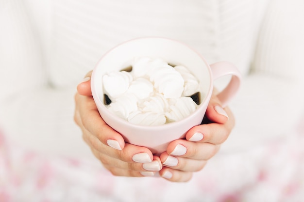 Photo beautiful female hands holding cup with coffe and marshmallows