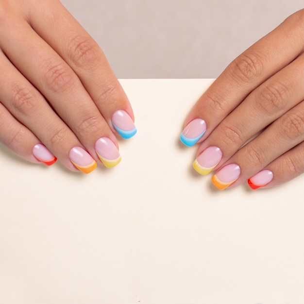 Belle mani femminili con unghie colorate per manicure con design arcobaleno