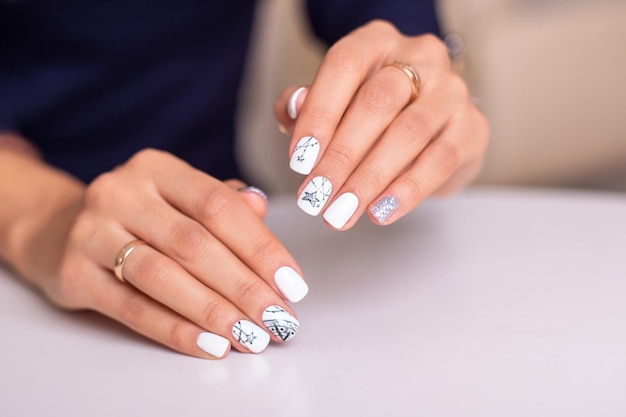 Beautiful female hands with fashion manicure nails white and silver gel polish stars design