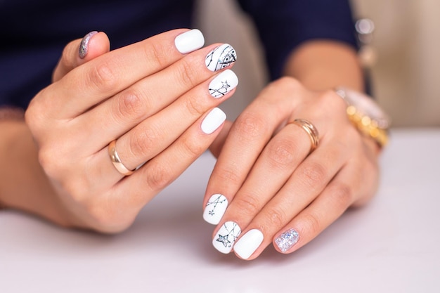 Beautiful female hands with fashion manicure nails, white and silver gel polish, stars design