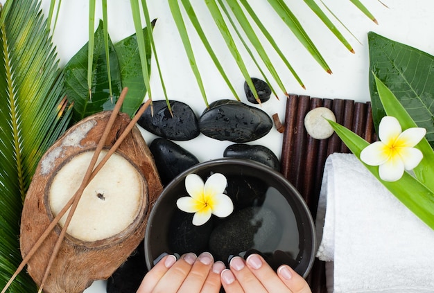 Beautiful female hands with flowers green leaves towel Spa manicure