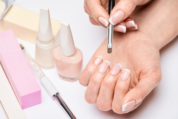 Beautiful female hands with french manicure over light grey surface