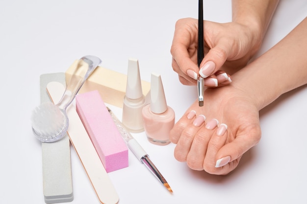 Beautiful Female Hands with French manicure over light grey surface