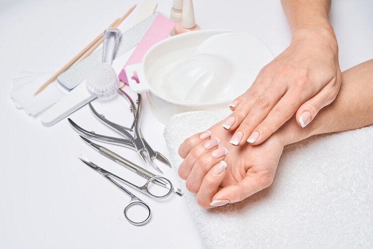 Beautiful Female Hands with French manicure over light grey surface