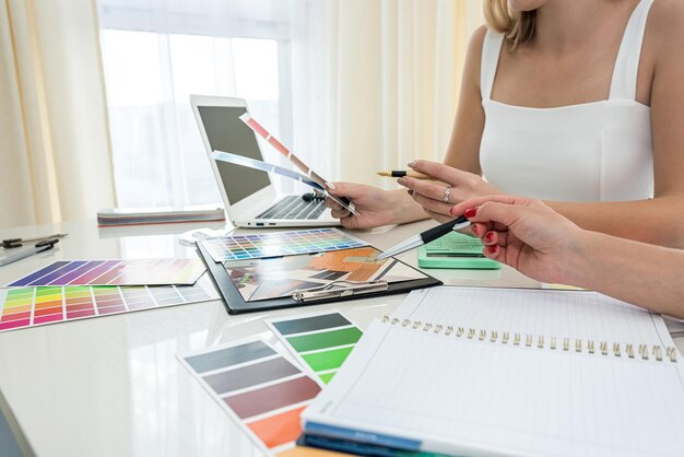 Beautiful female hands with manicure working with color
swatches to design rooms on the table samples concept the concept
of colors design concept