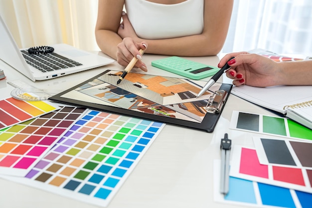 Beautiful female hands with manicure working with color swatches to design rooms on the table