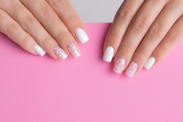 Foto bellissime mani femminili con unghie manicure rosa e bianche disegno floreale