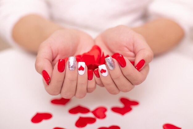 Beautiful female hands with red manicure nails hearts design on white background