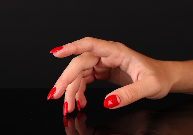 Beautiful female hands with red nails isolated on black