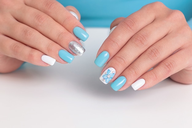 Beautiful female hands with romantic manicure nails blue and white gel polish