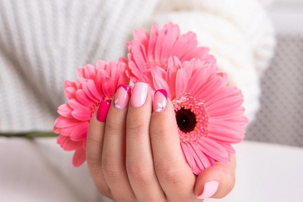 Beautiful female hands with romantic manicure nails pink gel polish gerbera flowers design