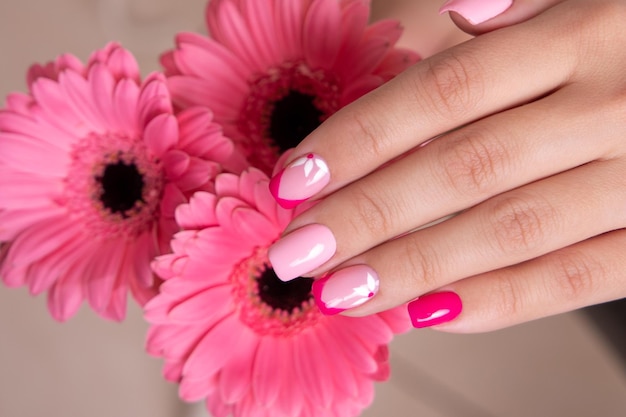 Beautiful female hands with romantic manicure nails pink gel polish gerbera flowers design