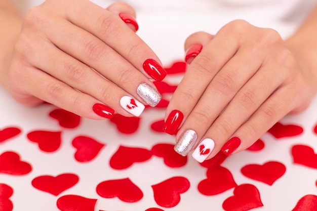 Beautiful female hands with romantic manicure nails red gel polish hearts and valentine design