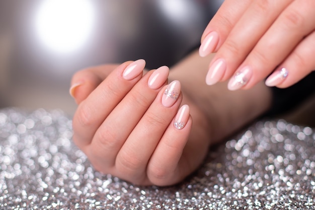 Beautiful female hands with wedding manicure nails pink gel polish with silver glitter