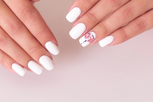 Beautiful female hands with white manicure nails, peonies design