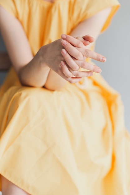 Photo beautiful female hands on a yellow background. take care of your hand. delicate palm with natural manicure, clean skin. light pink nails