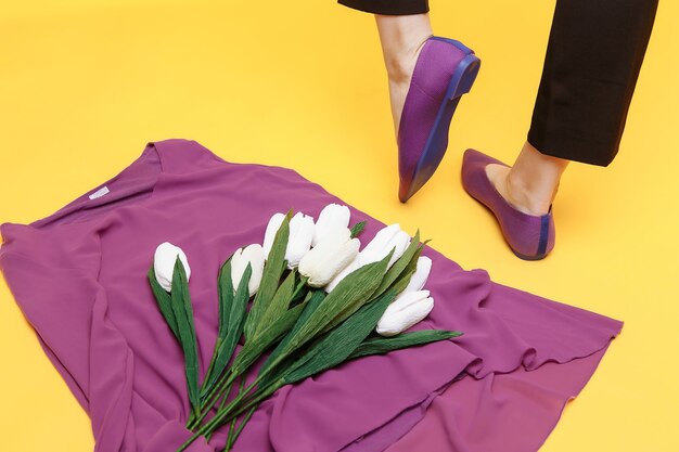 Beautiful female legs are dressed in stylish violet flat shoes.