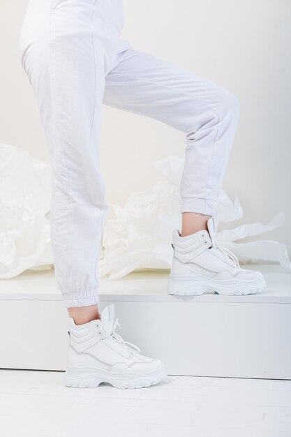 写真 白いズボン、白い革のスニーカーで美しい女性の脚。女性のカジュアルシューズの新しいコレクション