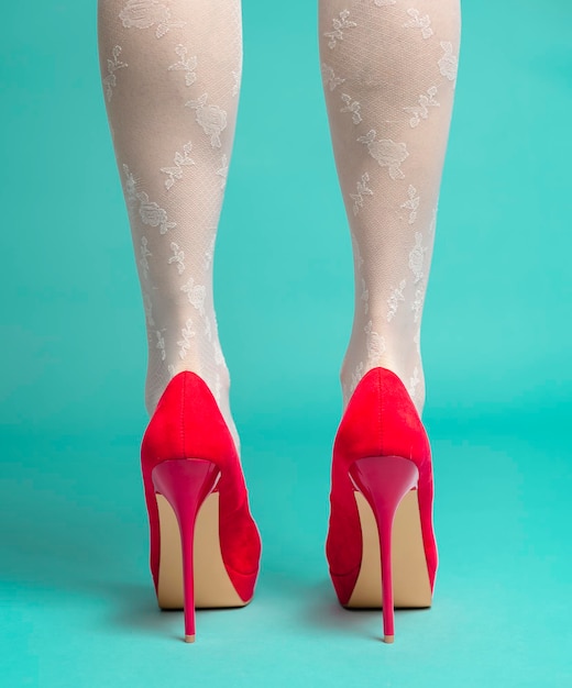 beautiful female legs wearing red high hills. isolated on blue background