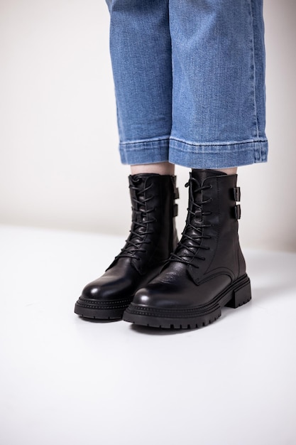 Beautiful female legs with fashionable black boots on the background in the studio. Women's stylish leather boots.