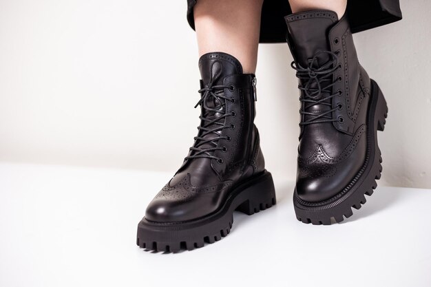 Beautiful female legs with fashionable black boots on the background in the studio. Women's stylish leather boots.