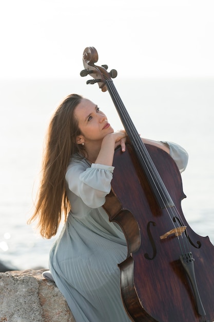 Photo beautiful female musician posing with cello outside