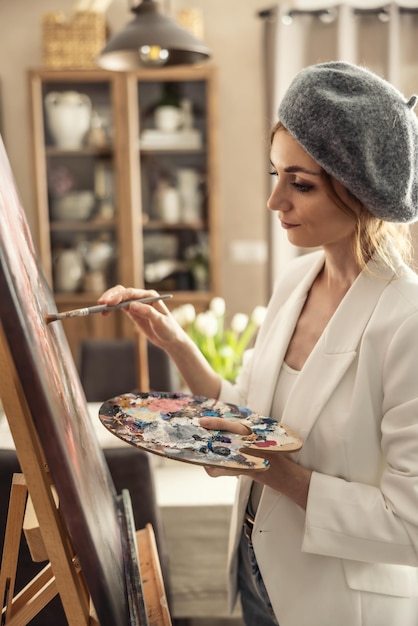 Foto bella pittrice che si diverte a dipingere in uno studio d'arte a casa