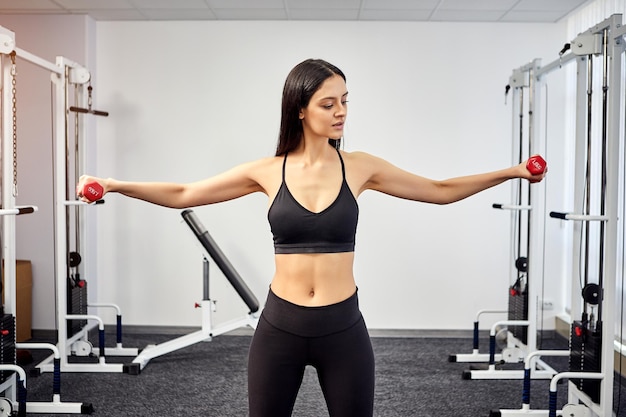 Beautiful female patient trains in rehabilitation kinesio\
clinic using dumbbells