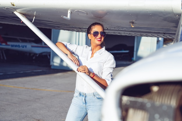 Beautiful female pilot in the hangar doing a pre-flight preparation