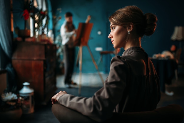 Beautiful female poseur, painter against easel