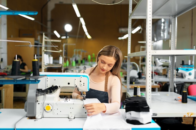 Beautiful female seamstress working with fabric at her workplace in textile plant