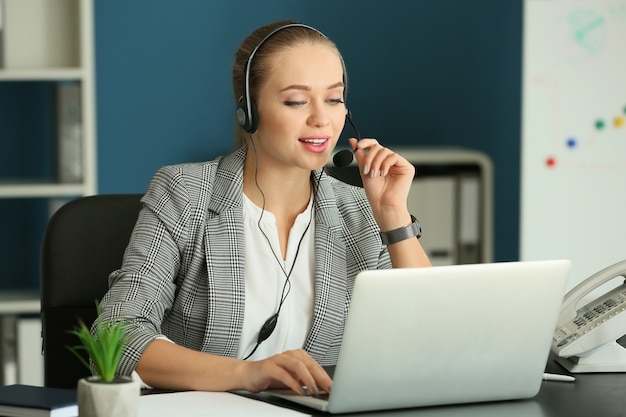 Beautiful female secretary talking through headset in office