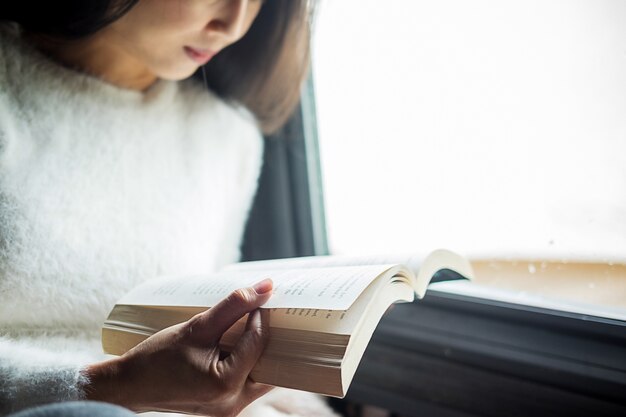 Beautiful female sitting on the bed and reading a book