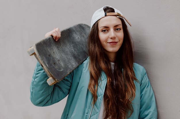 Bello pattinatore femminile che tiene il suo skateboard Foto Premium