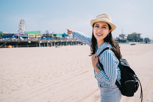 a beautiful female tourist pointing to the amusement park with an exciting face