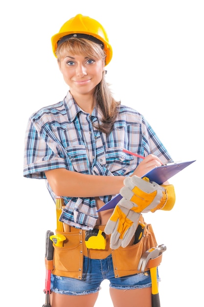 Beautiful female worker wearing sleeveless shirt with many construction tools writing in clipboard and looking at camera isolated