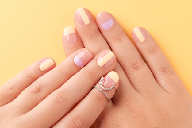 Beautiful females hands with manicure on yellow background trendy minimal spring summer nail design