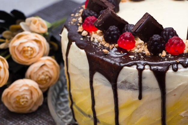 Beautiful festive cake with chocolate icing and marmalade on a background of flowers