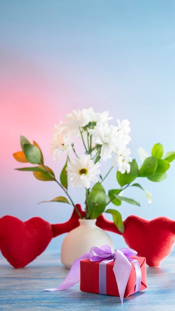 Beautiful festive still life on the theme of Valentine's Day with a gift, hearts and flowers.