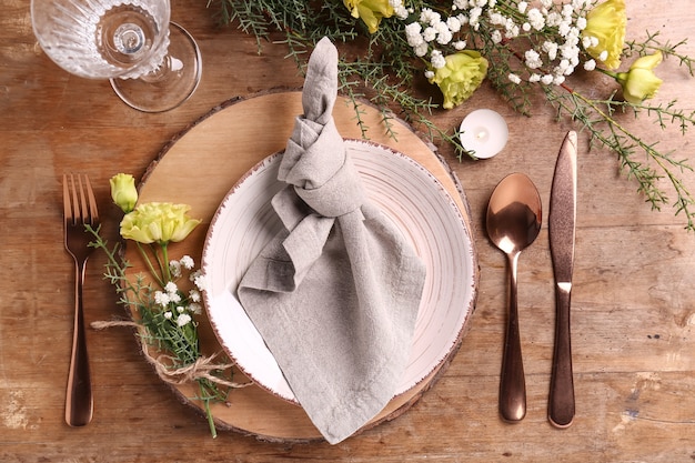 Beautiful festive table setting with floral decor on wooden background