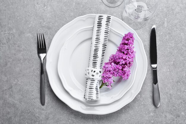 Beautiful festive table setting with lilac flower decor on grey surface