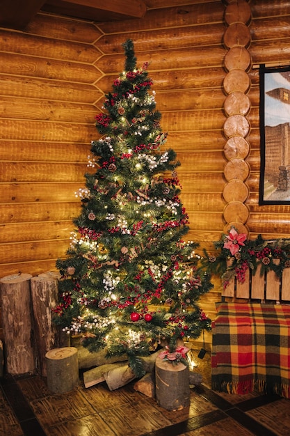 Beautiful fir tree decorated by fairy lights and toys in wooden
house christmas mood