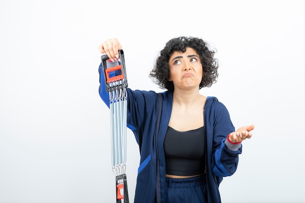 beautiful fit curly haired woman with chest expander standing.