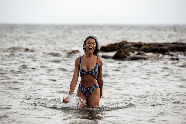 Beautiful fit playful black woman in bikini in a volcanic beach in Santo Antao, Cape Verde