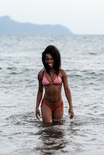 Beautiful fit playful black woman in bikini in a volcanic beach in Santo Antao, Cape Verde